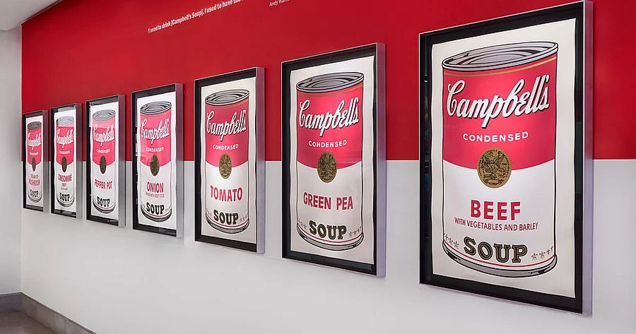 Andy Warhol egyenként keretezett Campbell's leveseskonzerv-nyomatai egy piros falon