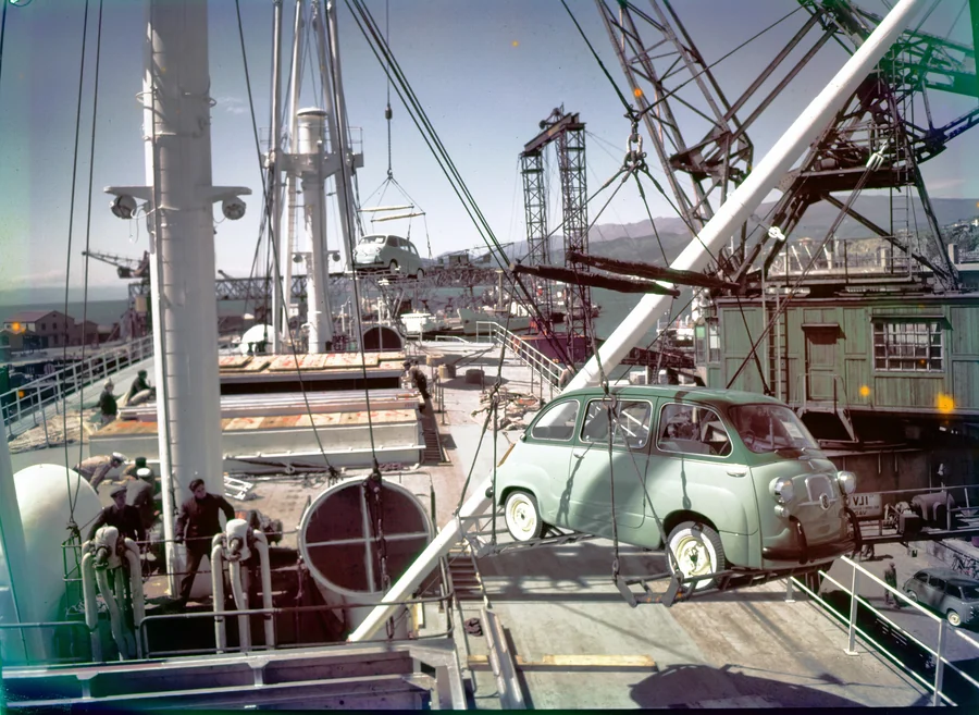 Zöld Fiat 600 Multiplát daruznak egy hajó fedélzetére a kikötőben