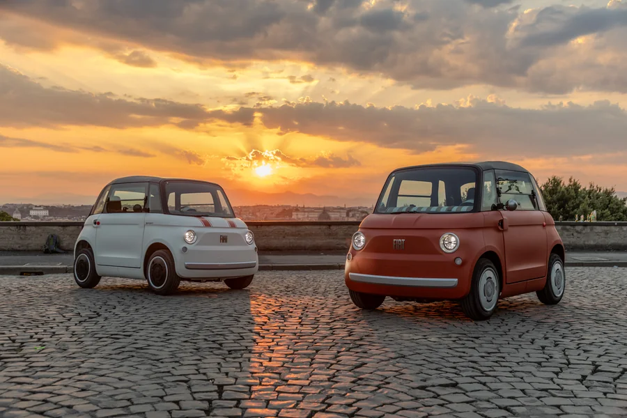 Két Fiat Topolino mopedautó naplementében, Róma látképével a háttérben