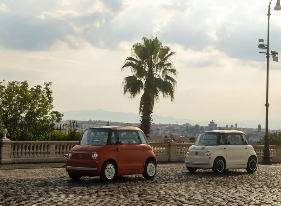 Két Fiat Topolino egy pálmafa előtt, Róma panorámájával