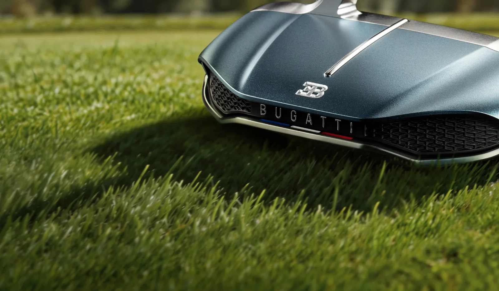 Bugatti karosszériát idéző Honma putter a fairway gyepén