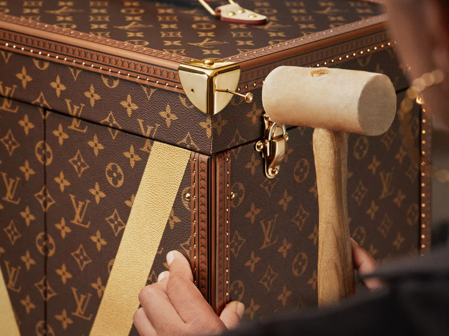 A Louis Vuitton láda aranyozott sárgaréz sarka és zárja közelről, kézműves fakalapáccsal