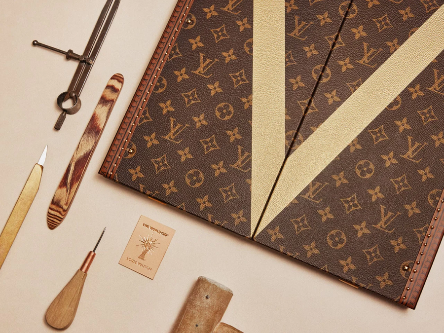 A Louis Vuitton láda sarka az arany V betűvel, kézműves szerszámokkal és FIFA-világbajnoki bőrcímkével