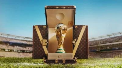 A FIFA-világbajnoki trófea a nyitott Louis Vuitton monogramos utazóládában egy stadion gyepén