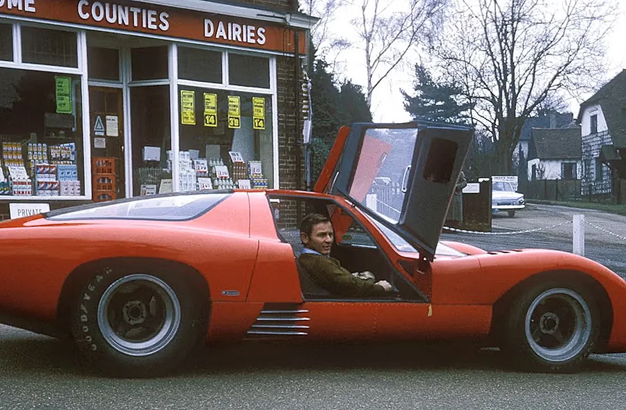 Az eredeti, korabeli McLaren M6GT egy vintage fotón, a vezetőülésben Bruce McLarennel