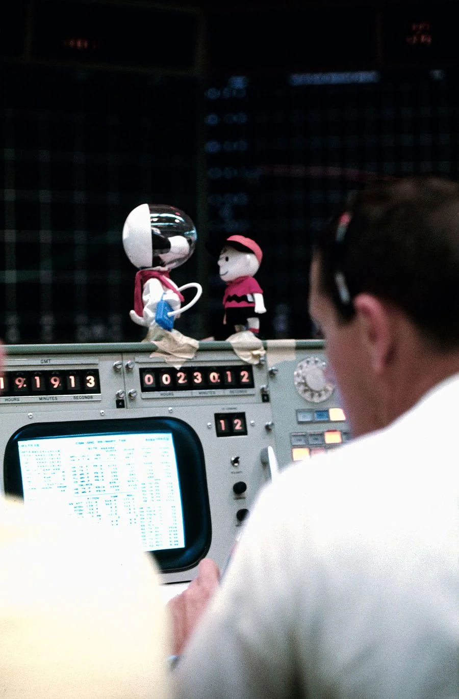 Snoopy és Charlie Brown űrhajós figurája egy NASA repülésirányító pult tetején
