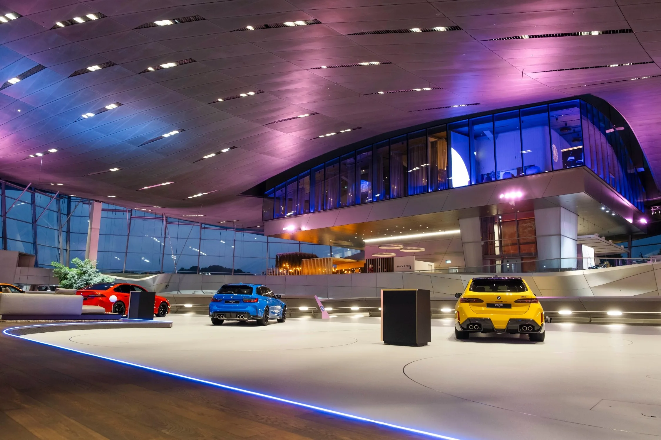 A BMW Welt kiállítótere BMW modellekkel, felette az üvegfalú THE CLOUD étteremmel