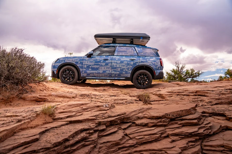 Az álcázott Mini Countryman oldalnézetből, sziklás terepen