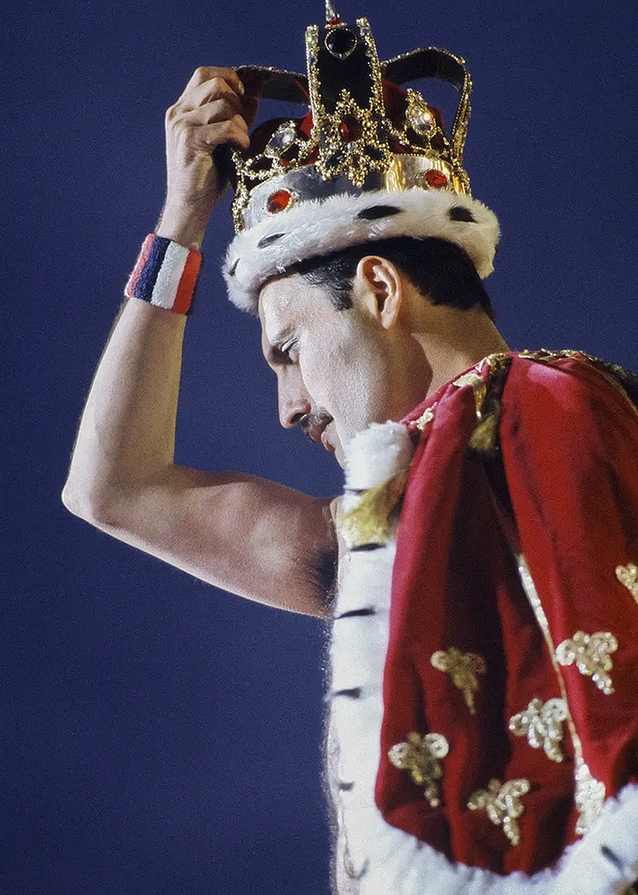 Freddie Mercury hermelinszegélyes vörös palástban és koronában a színpadon