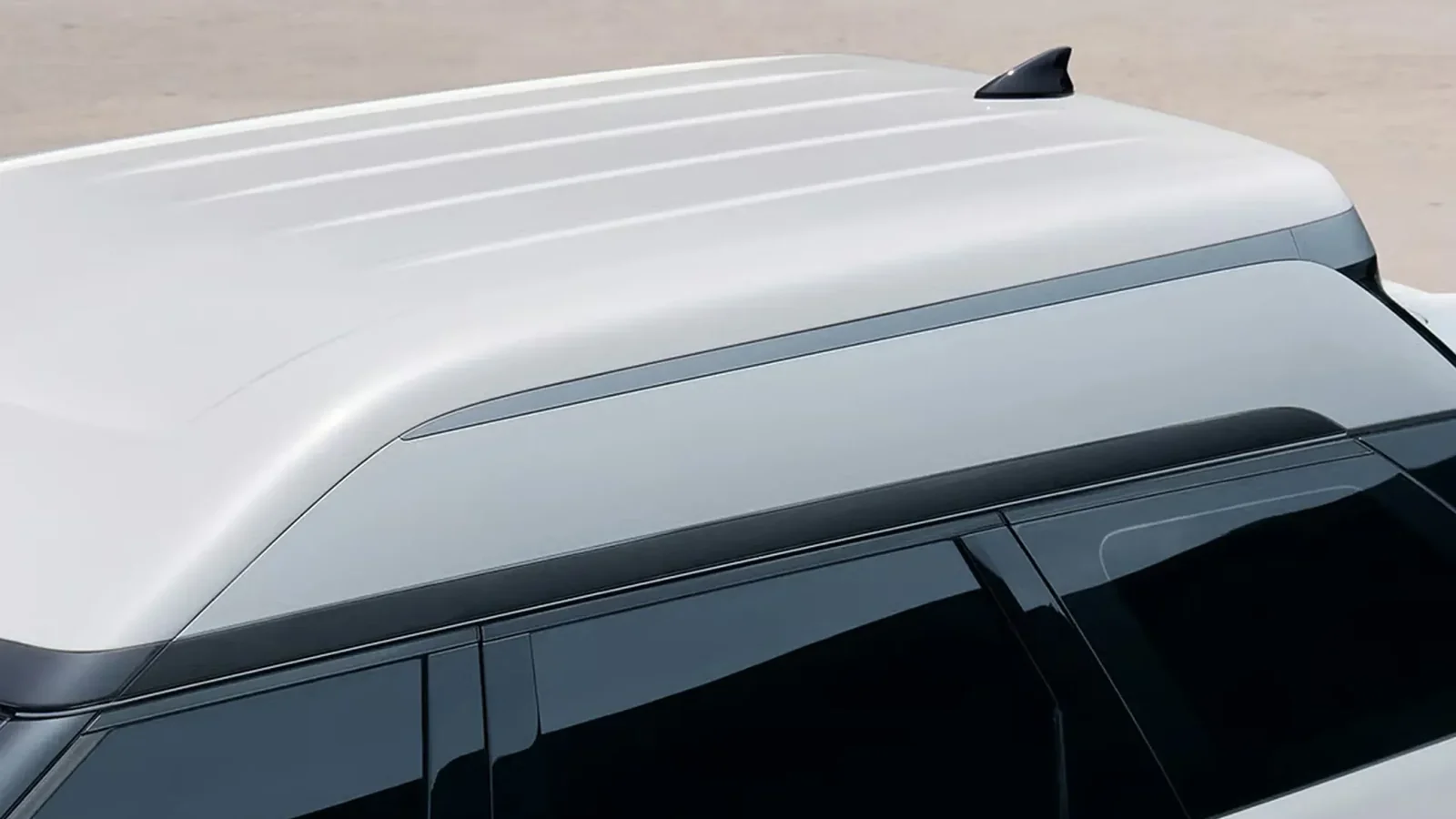 A fehér SUV megemelt tetőszerkezete és cápauszony antennája felülnézetből