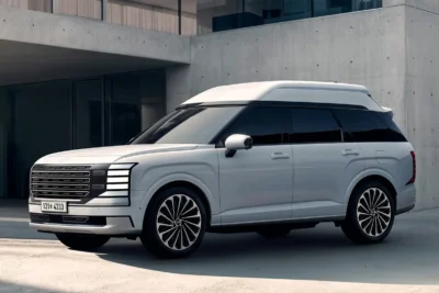 Fehér színű Hyundai Palisade High Roof terepjáró egy modern épület előtt parkolva